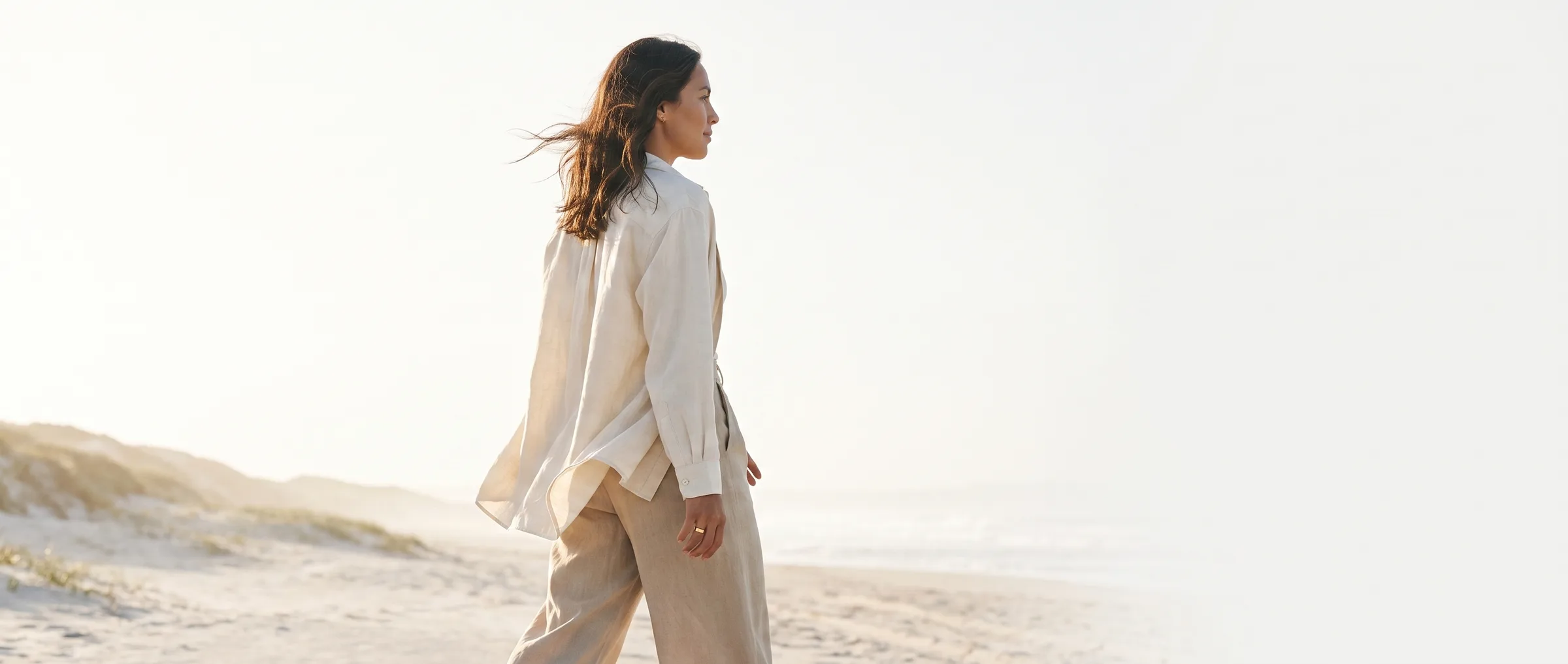 Woman walking along a pale coastal path in soft morning light